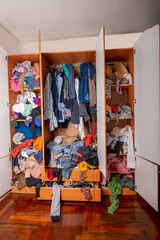Huge closet filled with used clothes, sloppily shoved and hanging from shelves and hangers....
