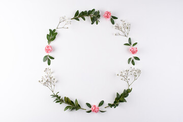 Wreath frame made of flowers branches, eggs and shells on a white background.