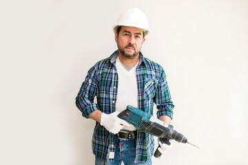 Male construction worker in a protective helmet with a perforator on a white background