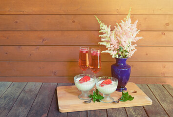 Rose champagne, italian dessert panna cotta  and astilbe flowers on wooden table.