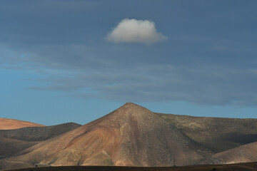 A volcanic mountain with a single cloud on top. Lanzarote, Spain.
