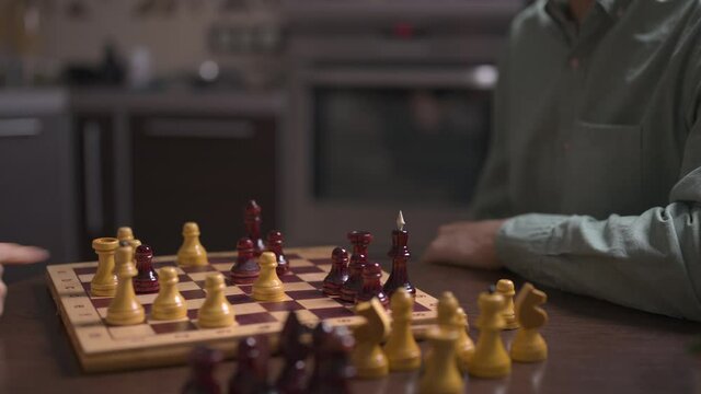 Man and woman playing chess at home. Camera slide movement