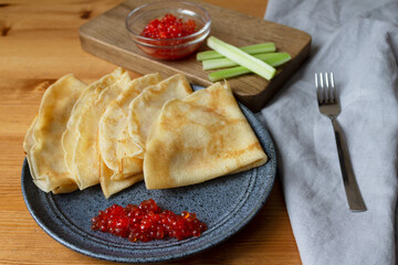 Ready-made nutritious breakfast dish Russian pancakes with milk with red caviar and celery.