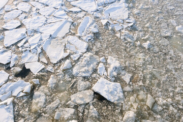 white and gray ice texture on a winter river, broken ice floe covered with snow with a textured surface, cracked and fragmented ice floating on frozen water on a cold day, icy pattern, background