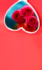 Romantic card, three pink roses are reflected in the mirror in the form of a heart. The concept of love confession, romantic setting, marriage proposal. Space for text on a red background.