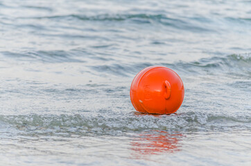 A red buoy on the surface of the water on the beach in Pefkochori, Greece