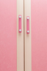 Nice pink cabinet doors with pink handles at different heights. Abstract concept.