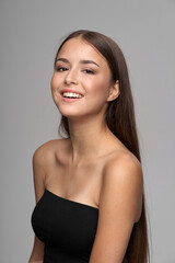 Fototapeta na wymiar Young beautiful female model close-up studio beauty portrait. Girl with natural make-up and long brunette straight hair. Happy smiling woman looking at you