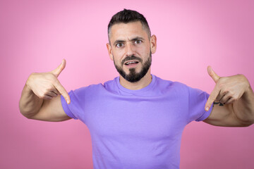 Young handsome man wearing casual t-shirt over pink background looking confident with smile on...
