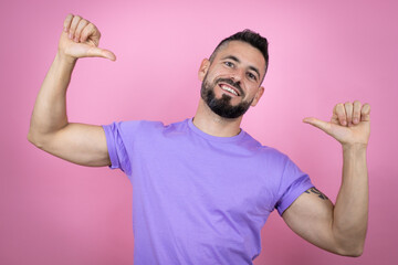 Young handsome man wearing casual t-shirt over pink background looking confident with smile on...