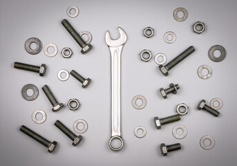 Bolts, nuts, washers and wrench on a gray background