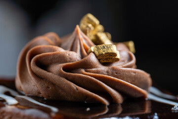 Piece of chocolate cake with cream and gold bars on it
