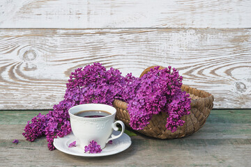 Romantic coffee break with white vintage cup and bunch of purple lilacs grapes on rustic wooden background
