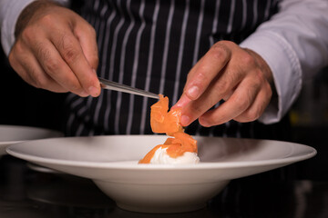 Chef cook preparing eggs in his kitchen. Eggs Benedict on toasted muffins with ham and sauce. Breakfast Buffet Concept, Breakfast Time. Various brunch on the table. 