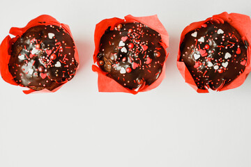 
Fresh chocolate muffins wrapped in red paper decorated with colorful hearts. Valentine's Day