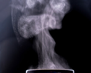 Steam over a cup. Liquid evaporation. Dark photo. Copy space.	