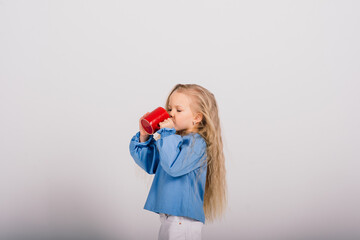 Little smiling child girl holding cup, isolated over white background. Studio shot.