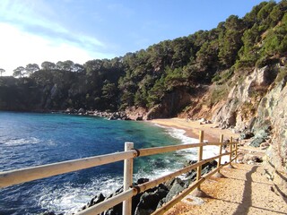 Camino a la playa de Porto Pi (Tossa de Mar), playa de arena gruesa y  piedras, rodeada de rocas y pequeños acantilados
