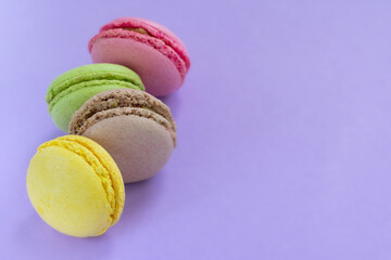 Row of french almond macarons with fillings on purple background with copy space