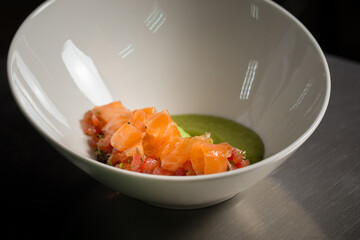 Chef cook preparing salad with salmon and avocado in his kitchen. Freezer food prepare in process vegetarian salad by chef hand in home kitchen. Dark black background with Text area for design menu 