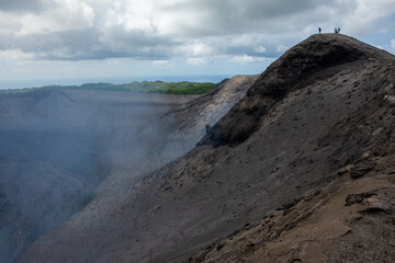 Tourists stand atop the crater rim, Mount Yasur volcano, Tanna Island, Vanuatu.