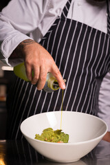 Chef cook preparing salad with salmon and avocado in his kitchen. Freezer food prepare in process vegetarian salad by chef hand in home kitchen. Dark black background with Text area for design menu 