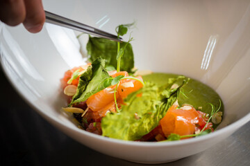 Chef cook preparing salad with salmon and avocado in his kitchen. Freezer food prepare in process vegetarian salad by chef hand in home kitchen. Dark black background with Text area for design menu 