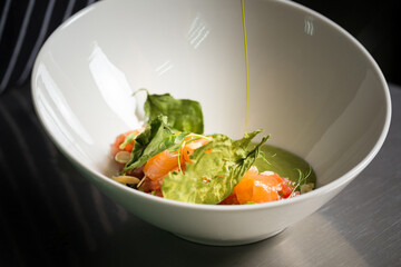 Chef cook preparing salad with salmon and avocado in his kitchen. Freezer food prepare in process vegetarian salad by chef hand in home kitchen. Dark black background with Text area for design menu 