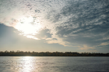 Dramatic sky with cirrus and cumulus clouds above the blue river. Idyllic summer scene. Panoramic view. Vacations, ecotourism, nature of Siberia