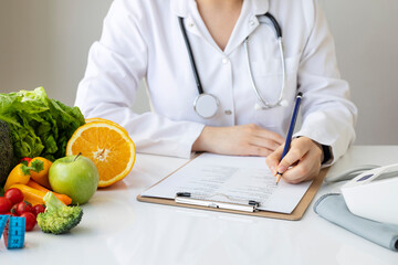 Female nutritionist doctor writing vegetable diet plan
