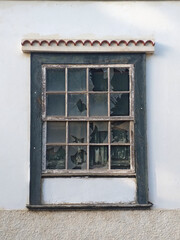 Traditional guillotine window in historic colonial house. Front view of closed old sash window on white concrete facade. Traditional architecture and construction.