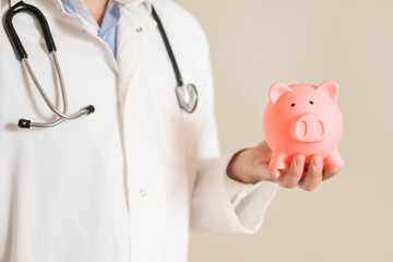 Image of male doctor holding piggy bank.