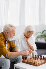 Senior couple playing chess on couch in living room