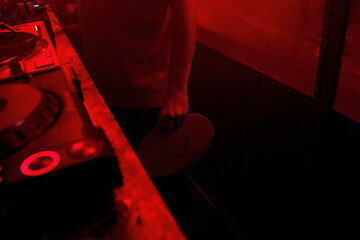 Parcial view of a deejay holding a vinyl record in his hand