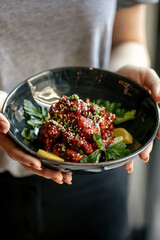 Girl holding a bowl of marinated chicken in spicy sauce with daikon 