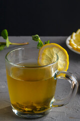 vitamin ginger drink with honey mint and lemon in a glass cup on a concrete background.