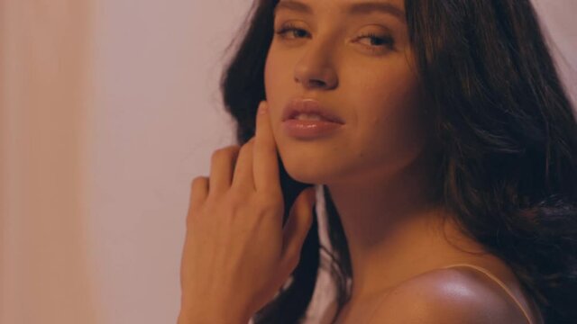 slow motion of young brunette woman with curly hair on white