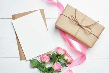 Greeting card with fresh roses and gift box on white background, mockup with copy space