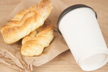 Two bun with poppy seeds with coffee cup on wood table. Breakfast. Good Morning