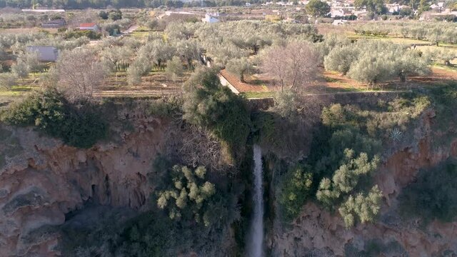 Gran cascada de agua junto a campo de olivos en plano a&eacute;reo de dron