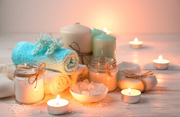 Candles, towels, soap and salt on the background of burning candles. Spa background, horizontal view.