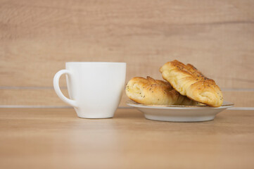 Two bun with poppy seeds with coffee cup on wood table. Breakfast. Good Morning