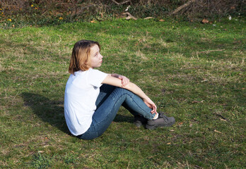 teenage girl sitting on the grass in the park on a sunny day