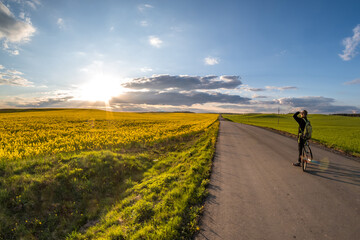 the cyclist stands on the road and looks into the distance and admires the beautiful landscape at...