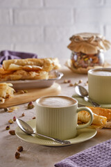 Fragrant cappuccino coffee with puff tubes with meringue and pistachios close-up