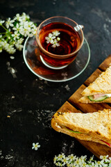 English sandwiches. Filling with tomato, dill and butter. The shape is triangular. A cup of tea is visible in the background. Blurred background. Copy space