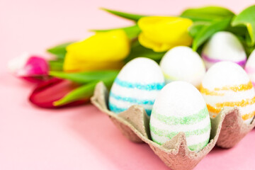 Easter painted eggs with tulips on a pink background. Copy space. Easter celebration concept.