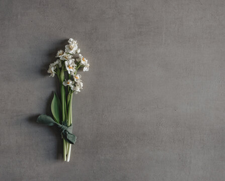 Kleiner Blumenstrau&szlig; mit Fr&uuml;hlingsblumen und einem gr&uuml;nen Band auf grauem Untergrund 
