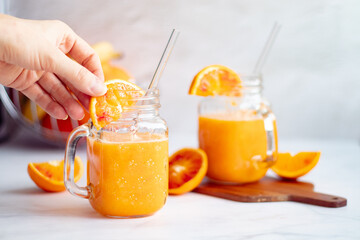 Homemade spring detox smoothie from oranges, carrots and banana in mason jar and glass straw