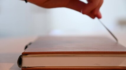 SLOW MOTION shallow focus side shot of a leather bound book being opened by pulling on the book ribbon marker
